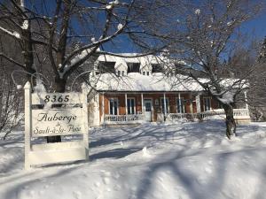 a house in the snow with a sign in front at Auberge du Sault-à-la-Puce in Chateau Richer