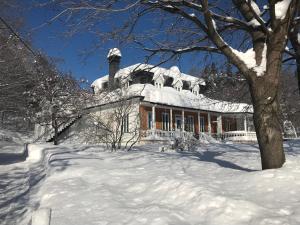 una casa cubierta de nieve en un patio cubierto de nieve en Auberge du Sault-à-la-Puce, en Chateau Richer