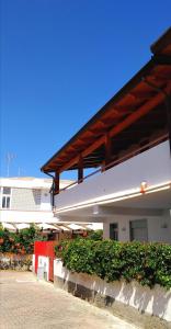un edificio blanco con una valla roja y algunos arbustos en Casa Filippa & Case Charlotte, Mongiove al mare, en Mongiove