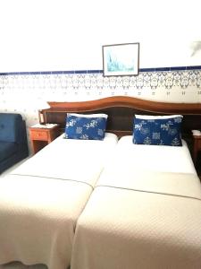 two beds with white sheets and blue pillows at Hotel Atlântica in São Martinho do Porto