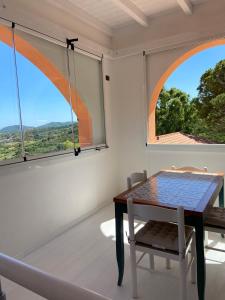 Residence Le Solane في مارينا دي كامبو: غرفة طعام بها نافذتين كبيرتين وطاولة