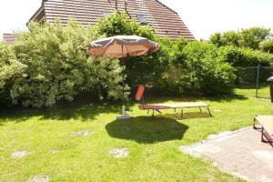 einen Tisch, einen Regenschirm und einen Stuhl im Hof in der Unterkunft Ferienhaus Marion in Neßmersiel