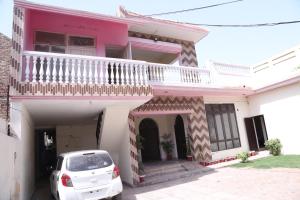 a white car parked in front of a pink house at Hotel Sereena residence in Multan