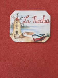 um sinal numa parede com uma imagem de um moinho de vento em LA NICCHIA em Marsala