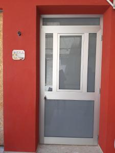 uma porta branca com uma janela numa parede vermelha em LA NICCHIA em Marsala