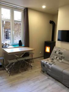 a living room with a table and a couch and a tv at gite 4 Pers coeur de village in Jujurieux