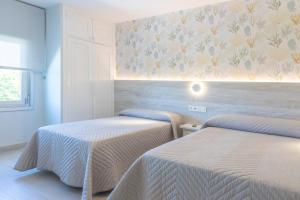 2 camas en una habitación con una pared con flores en Hotel Leal - La Sirena, en Villanueva de Arosa