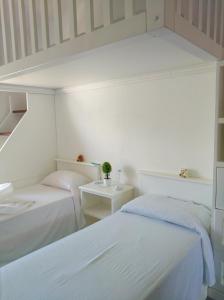 2 Betten in einem Zimmer mit weißen Wänden in der Unterkunft Agriturismo Aiolia - Panorama Eolie in Mongiove
