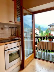 una cocina con una puerta corredera de cristal que da a un balcón en Casa Ortensia, en Pellizzano