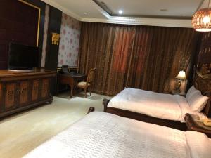 a hotel room with two beds and a television at Royal Garden Motel - Chiayi Branch in Chiayi City