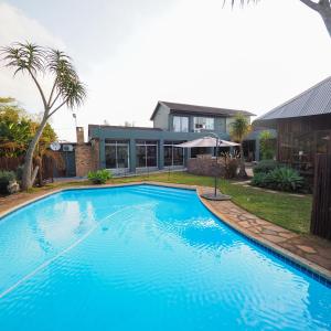 a large blue swimming pool in front of a house at Fever Tree Guesthouse in Hillcrest