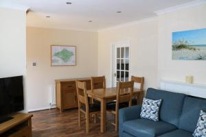 un soggiorno con tavolo e divano blu di Goldcrest Cottage a Sandown