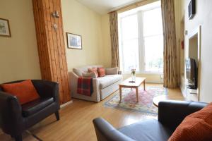uma sala de estar com um sofá e uma cadeira em Old Town View - Picture Perfect! em Edimburgo