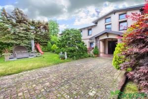 a house with a brick driveway in front of a yard at Willa Garden pokoje i apartament in Ustronie Morskie