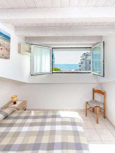 - une chambre avec un lit, une fenêtre et une chaise dans l'établissement Appartamenti Lignano Sabbiadoro - Villa Ammiraglia, à Lignano Sabbiadoro