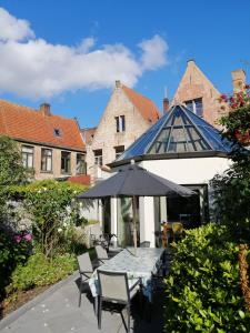une terrasse avec une table, des chaises et un parasol dans l'établissement B&B Huis Willaeys, à Bruges