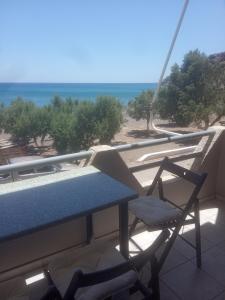 un tavolo e una sedia su un balcone con vista sulla spiaggia di Antoine Apartment Sea Side a Tsoutsouros