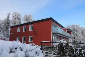 a red house with snow in front of it at Der Buchenhof in Braunlage