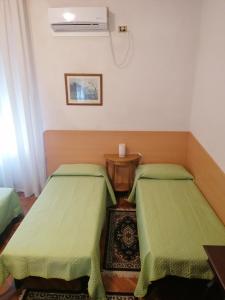 una camera con due letti verdi e un tavolo di Sacco Alloggi a Rovigo