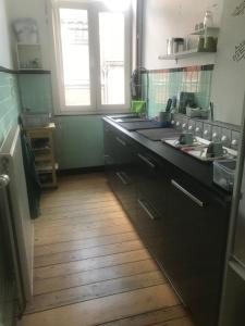 kuchnia z czarnymi szafkami i drewnianą podłogą w obiekcie Au 194 w mieście Liège