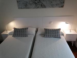 two beds in a bedroom with two lamps on a table at Attic+views+terrace+parking in Donostia-San Sebastián