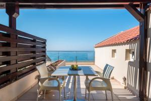 a blue table and chairs on a balcony with the ocean at Despina Apartments in Plataniás