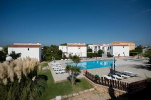 a resort with a swimming pool and lounge chairs at Apartamentos Sa Caleta in Sa Caleta