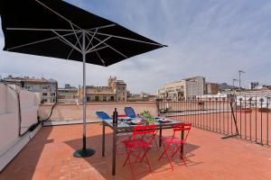 a table and chairs with an umbrella on a roof at Bcn Paseo De Gracia Rocamora Apartment in Barcelona