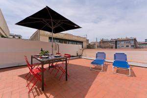 a patio table and chairs with an umbrella on a roof at Bcn Paseo De Gracia Rocamora Apartment in Barcelona