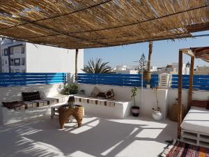 a patio with couches and tables and a straw umbrella at Dar Doudi in Sousse
