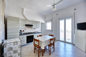 a white kitchen with a table and chairs in it at Red Fisherman’s House - OSTUNI Sea Front in Villanova di Ostuni