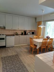 een keuken met witte kasten en een tafel en stoelen bij Kuusamon Keitaan Helmi in Joutsenniemi