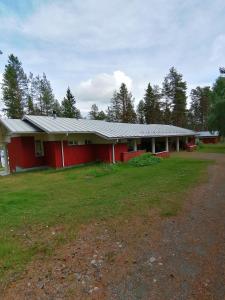 een rood gebouw met een tuin ervoor bij Kuusamon Keitaan Helmi in Joutsenniemi