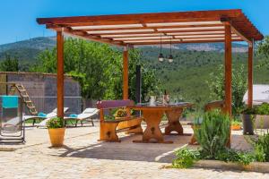 een houten pergola met een tafel en stoelen op een patio bij Villa R&B heated pool in Vrpolje