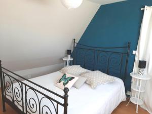 ein Schlafzimmer mit einem schwarzen Bett und einer blauen Wand in der Unterkunft Les Hortensias-chambre chez l'habitant in Bretteville-du-Grand Caux