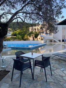 a table and chairs in front of a swimming pool at Cascade Holiday Resort in Poros