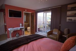 1 dormitorio con 1 cama y puerta corredera de cristal en Birdsong Cottage Bed and Breakfast en Chathill