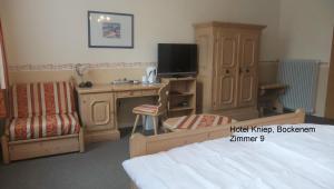 a bedroom with a bed and a desk and a tv at Hotel Kniep in Bockenem