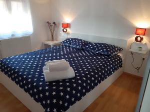 a bedroom with a blue and white bed with two pillows at Apartman Deni in Peroj