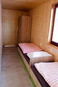 two beds in a wooden room with a door at Chaty U Cvrků in Orlík