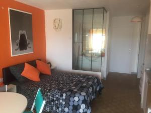 - une chambre dotée d'un lit avec un mur orange dans l'établissement Studio Naturiste PaulAna Héliopolis L39, au Cap d'Agde
