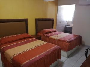 デリシアスにあるHOTEL BAEZAのベッド2台とシンク付きのホテルルームです。