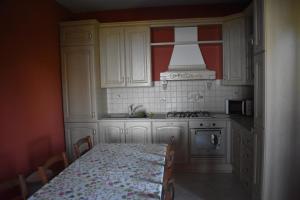 a kitchen with white cabinets and a table and a stove at Villa Di Martino in Vico Equense