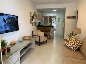 a living room with a couch and a tv on the wall at Vilage beira mar in Itacimirim