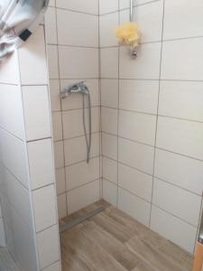 un bagno piastrellato bianco con doccia e tubo di Sobe SM0LEJ a Bled
