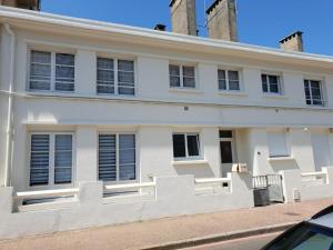 une maison blanche avec une clôture devant dans l'établissement Perle Berckoise - studio - 250m de la plage - 1er étage, à Berck-sur-Mer