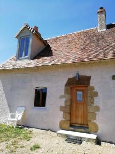 Casa blanca con puerta de madera y silla en Chez Pastuso, en Brigueuil-le-Chantre