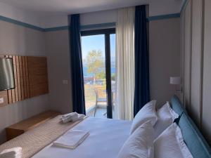 a bedroom with a bed with a large window at Hotel Olive Ksamil in Ksamil