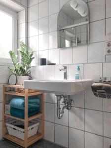 a bathroom with a sink and a mirror and towels at Wohlfühl-Apartment Sinsheim, Nähe Therme und Museum in Sinsheim