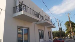 a white building with a balcony on the side of it at Nikko's apartments Elafonisos in Elafonisos